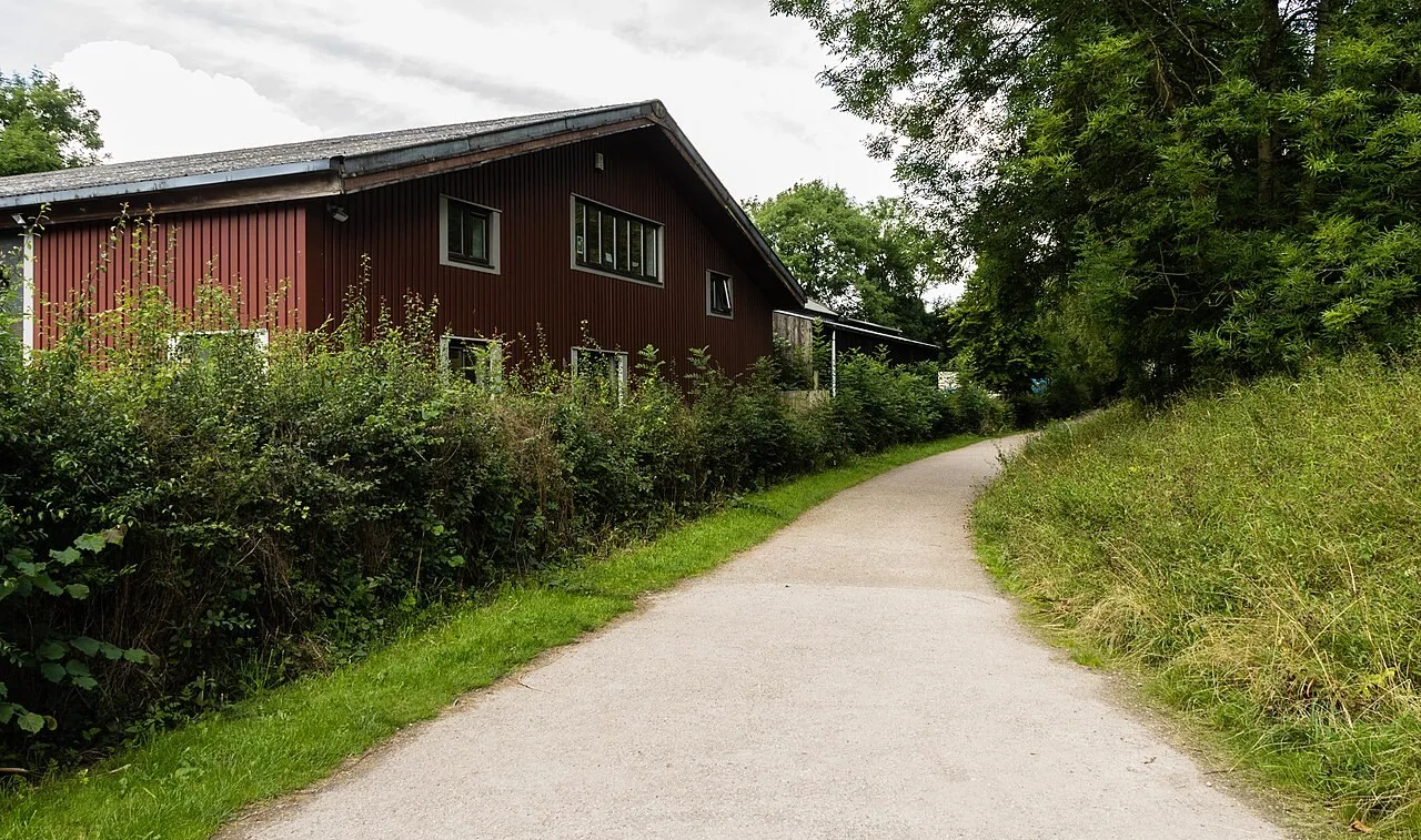 Surfaced Monsal Trail beside trees and a building at the Bakewell end of the route