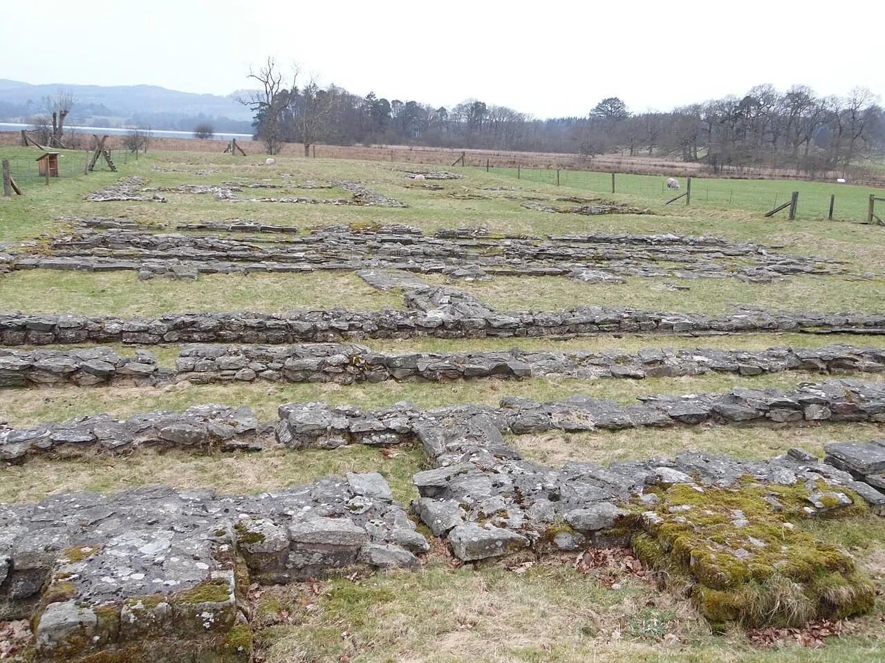Low stone foundations of Ambleside Roman Fort in open grass