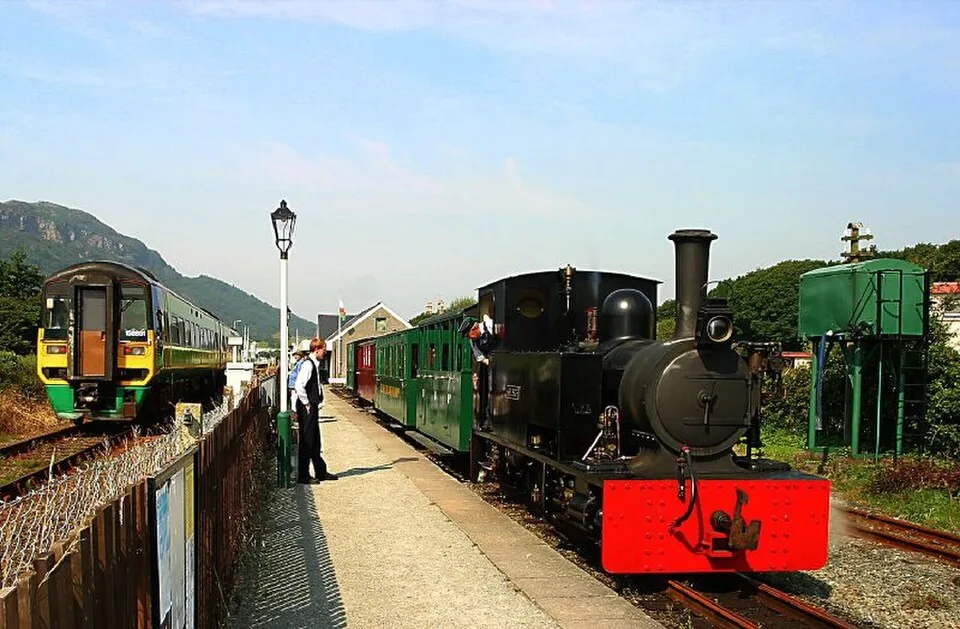 Welsh Highland Heritage Railway train with a main-line train passing at Porthmadog