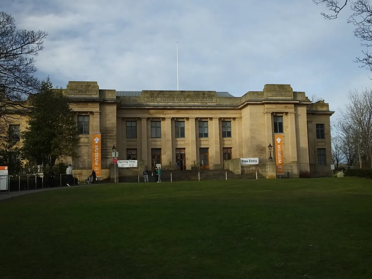 The classical stone front of the Great North Museum: Hancock, framed by trees and lawn