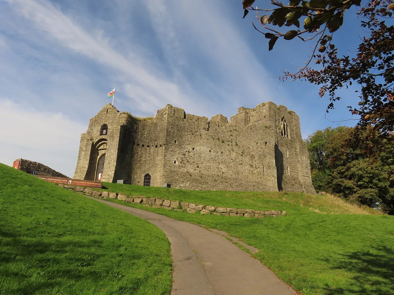Oystermouth Castle walls above a lawn and approach path in Mumbles