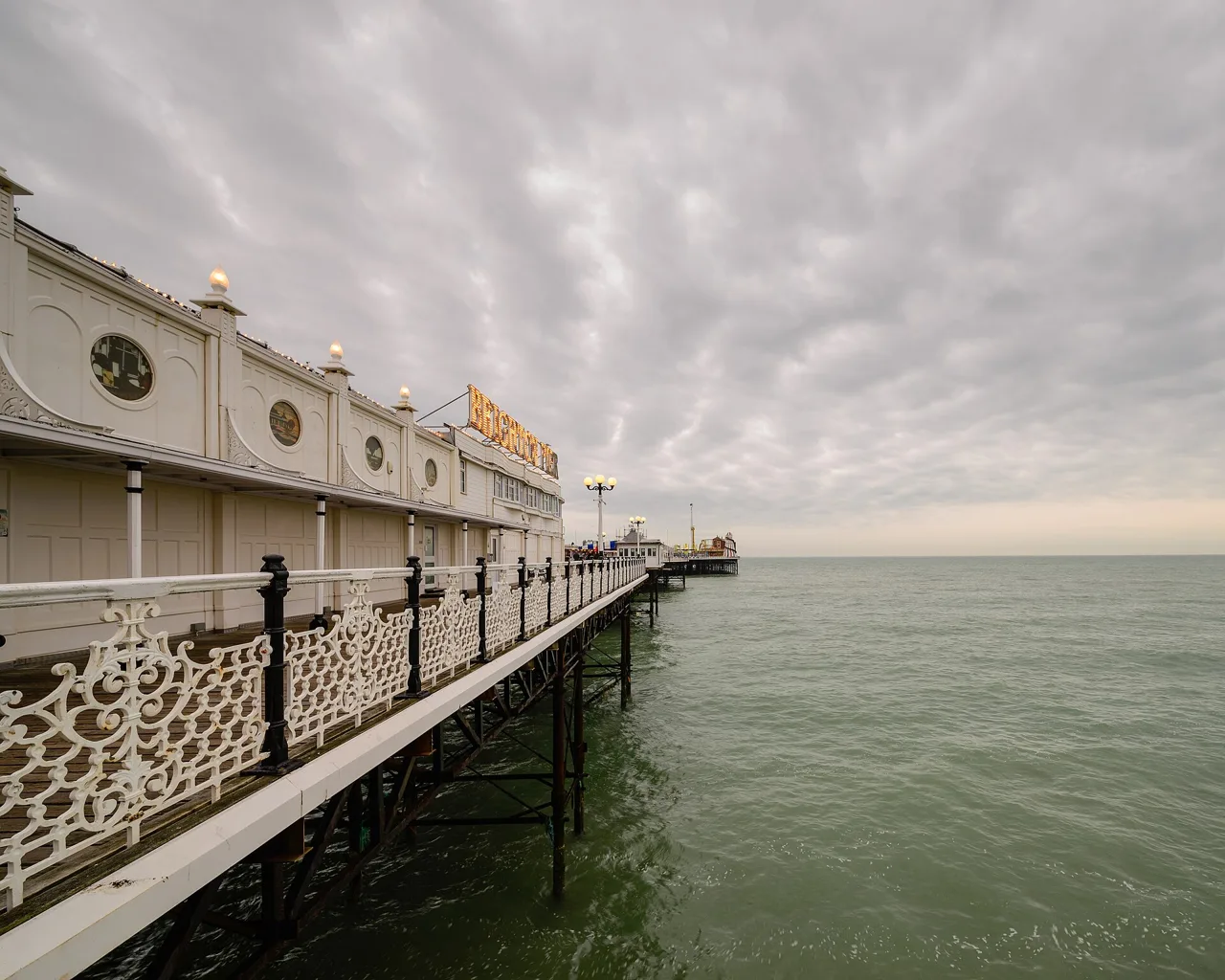 White railings and amusement buildings extending over the sea on Brighton Palace Pier