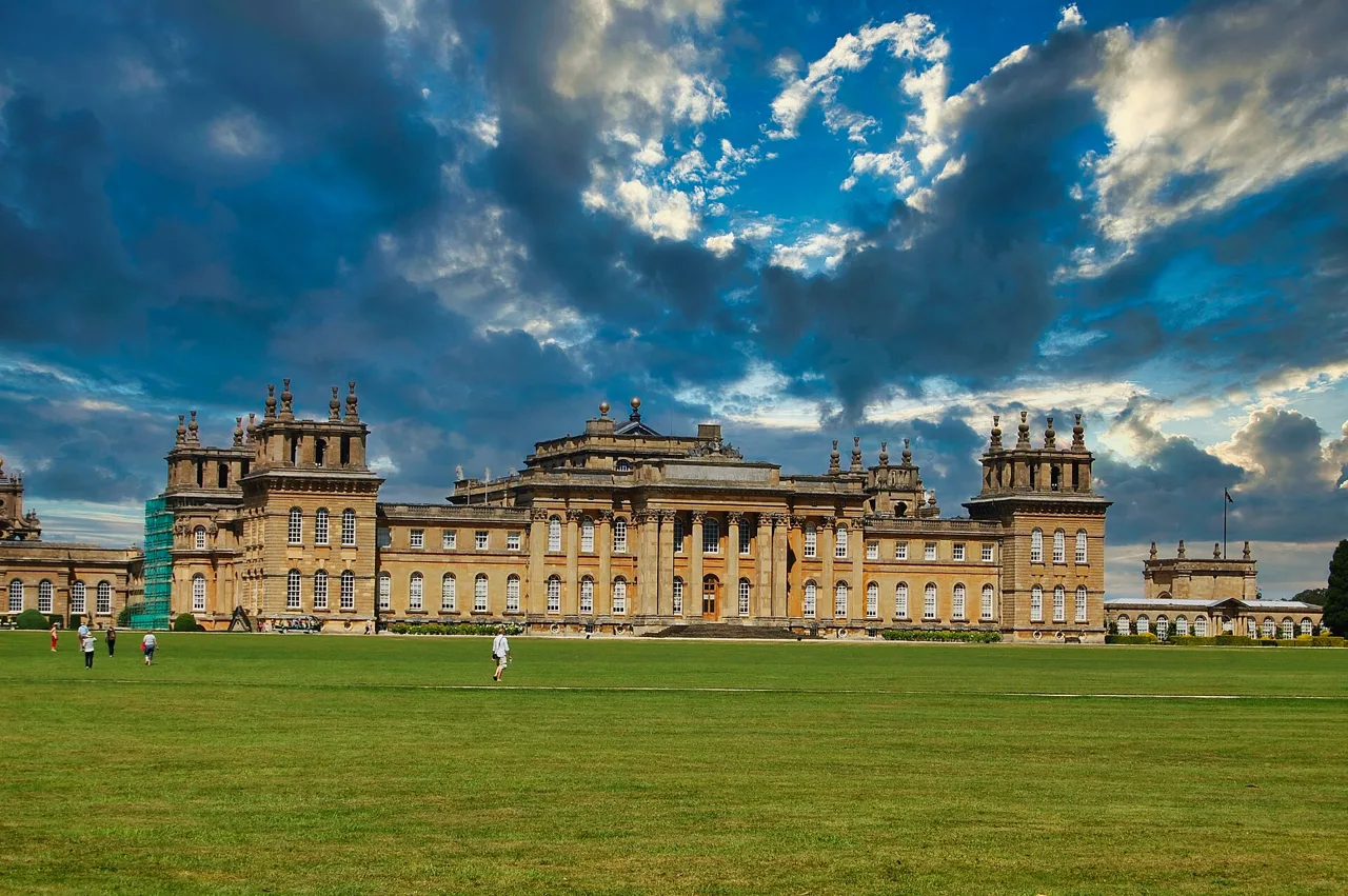 Blenheim Palace seen across its lawn beneath a cloudy sky