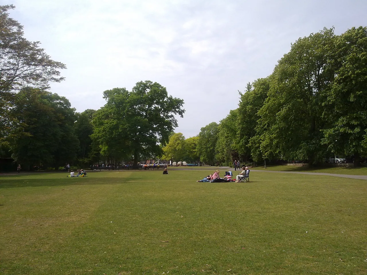 Visitors resting on lawns among mature trees in Alexandra Gardens