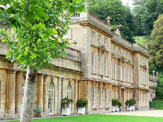 The stone country house at Dyrham Park framed by trees