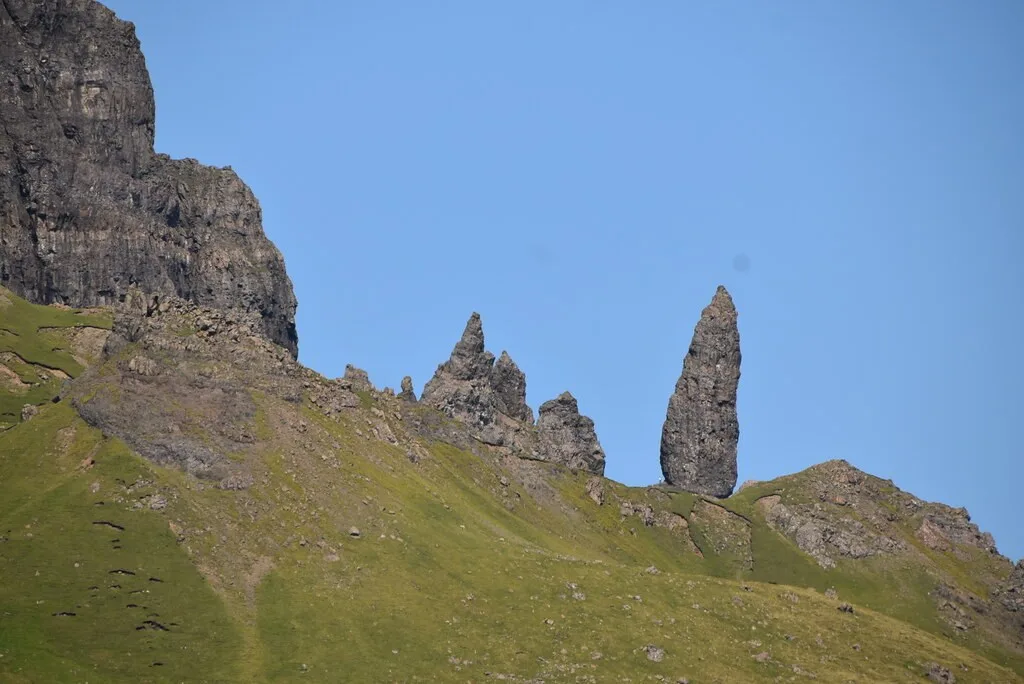 Rock pinnacles of the Old Man of Storr rising above a steep grassy slope