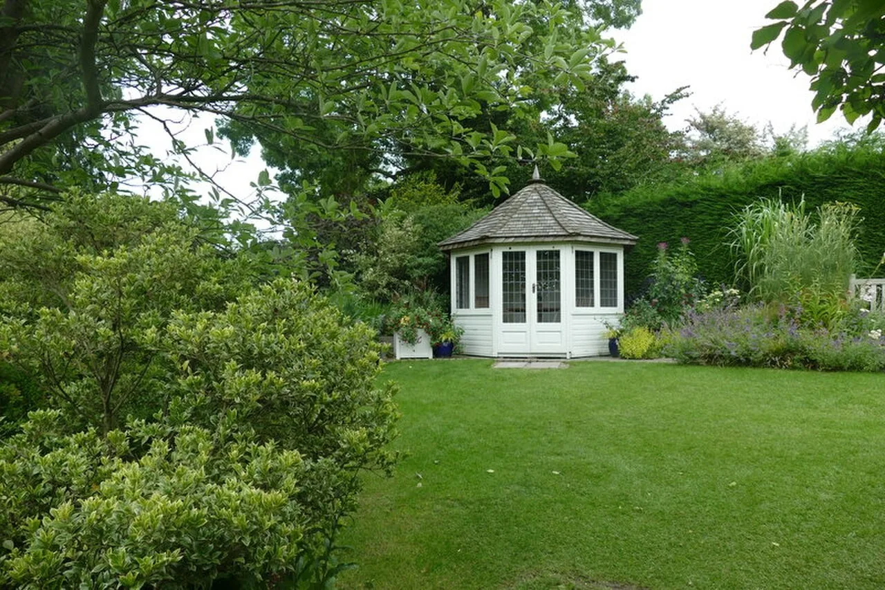 Summer house and lawn surrounded by planting at RHS Garden Harlow Carr
