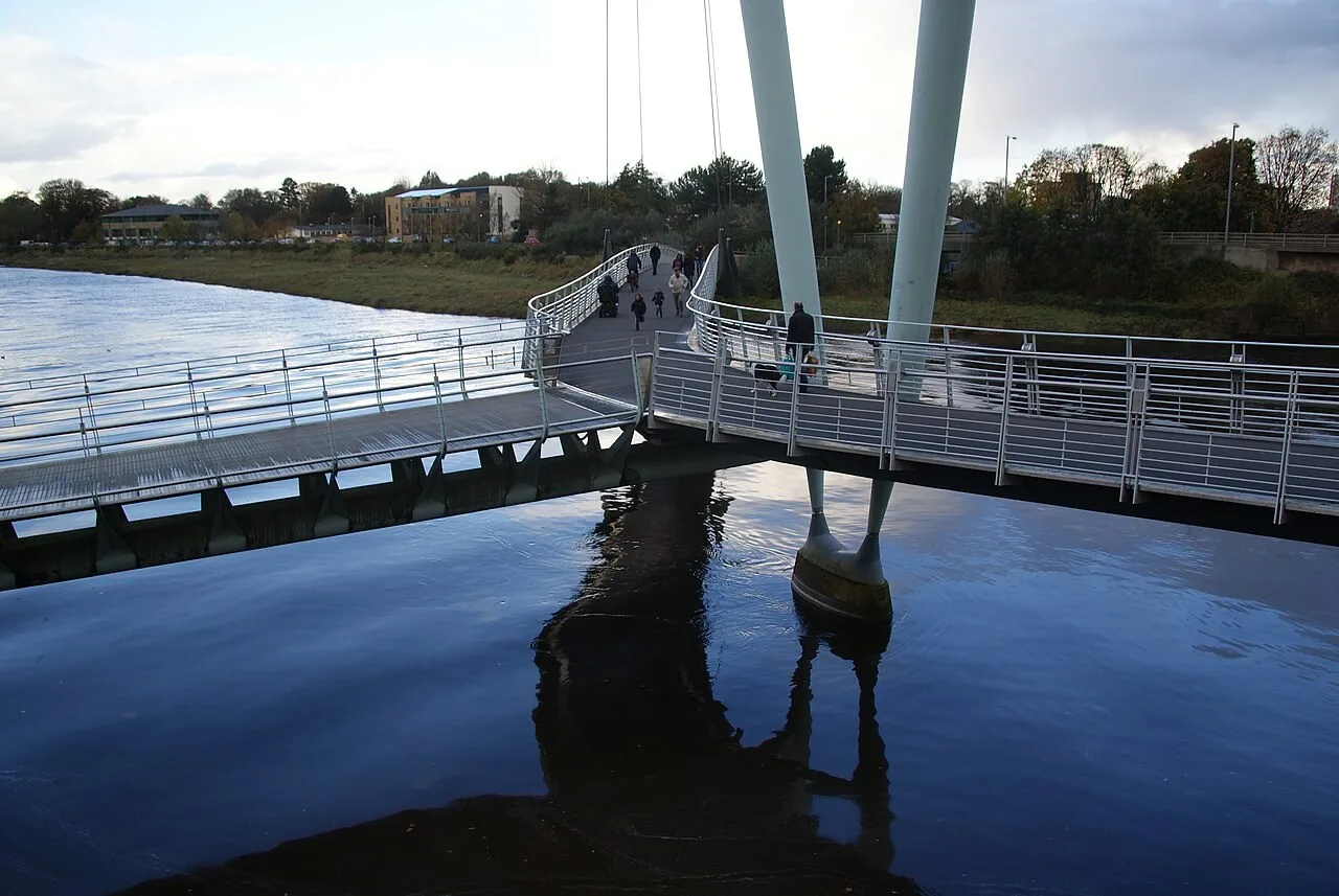 Pedestrians on the curved white deck of Lancaster’s Millennium Bridge over the River Lune