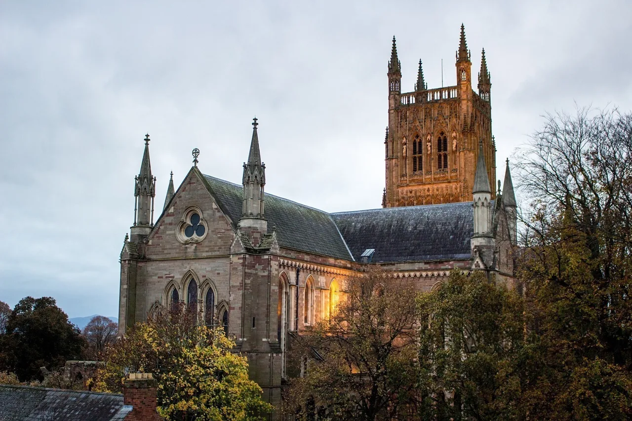 Worcester Cathedral and its square tower lit against an evening sky