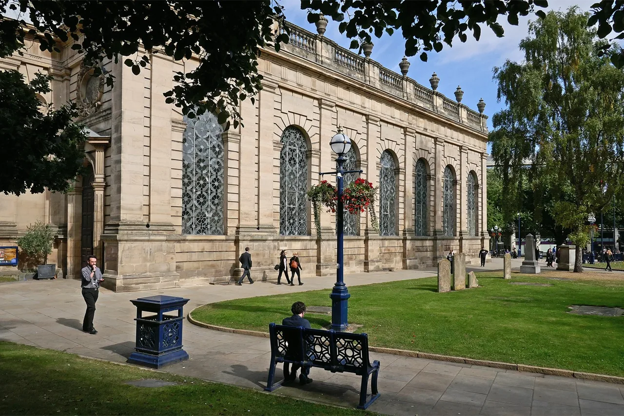Birmingham Cathedral beside trees, benches and a path in Cathedral Square
