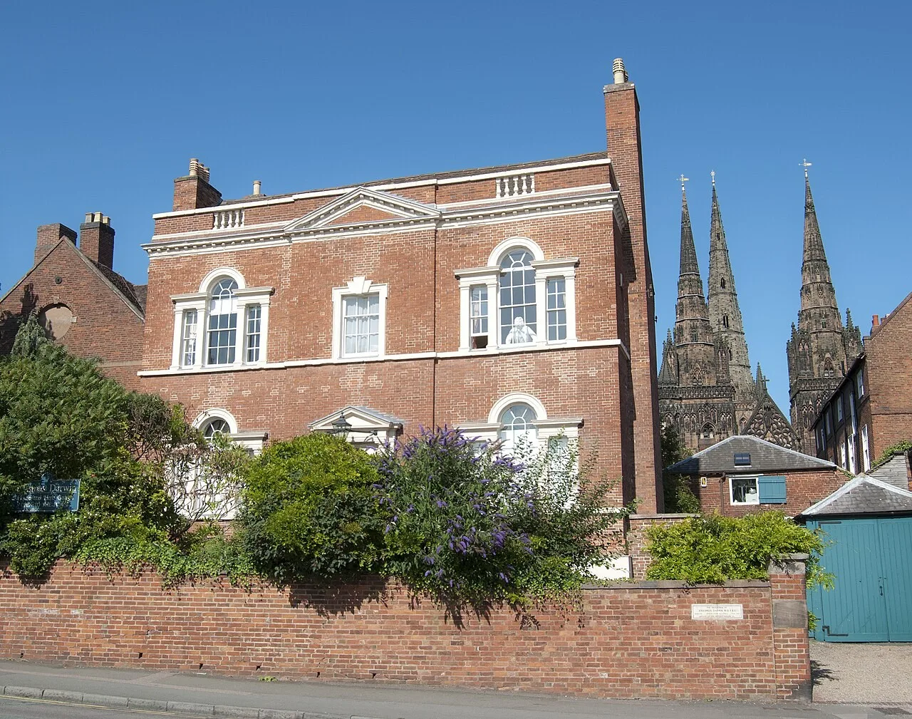 Red-brick Erasmus Darwin House and herb garden with Lichfield Cathedral spires behind