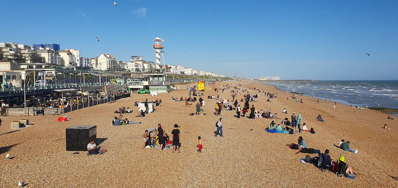 People on Brighton’s shingle beach beside the seafront promenade