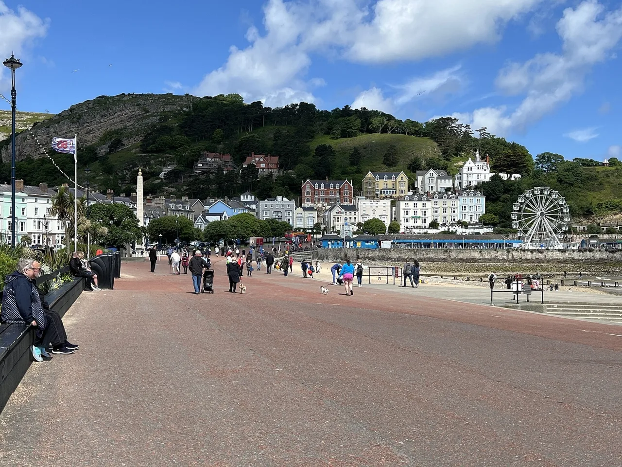 People walking on Llandudno promenade below the Great Orme and seafront hotels