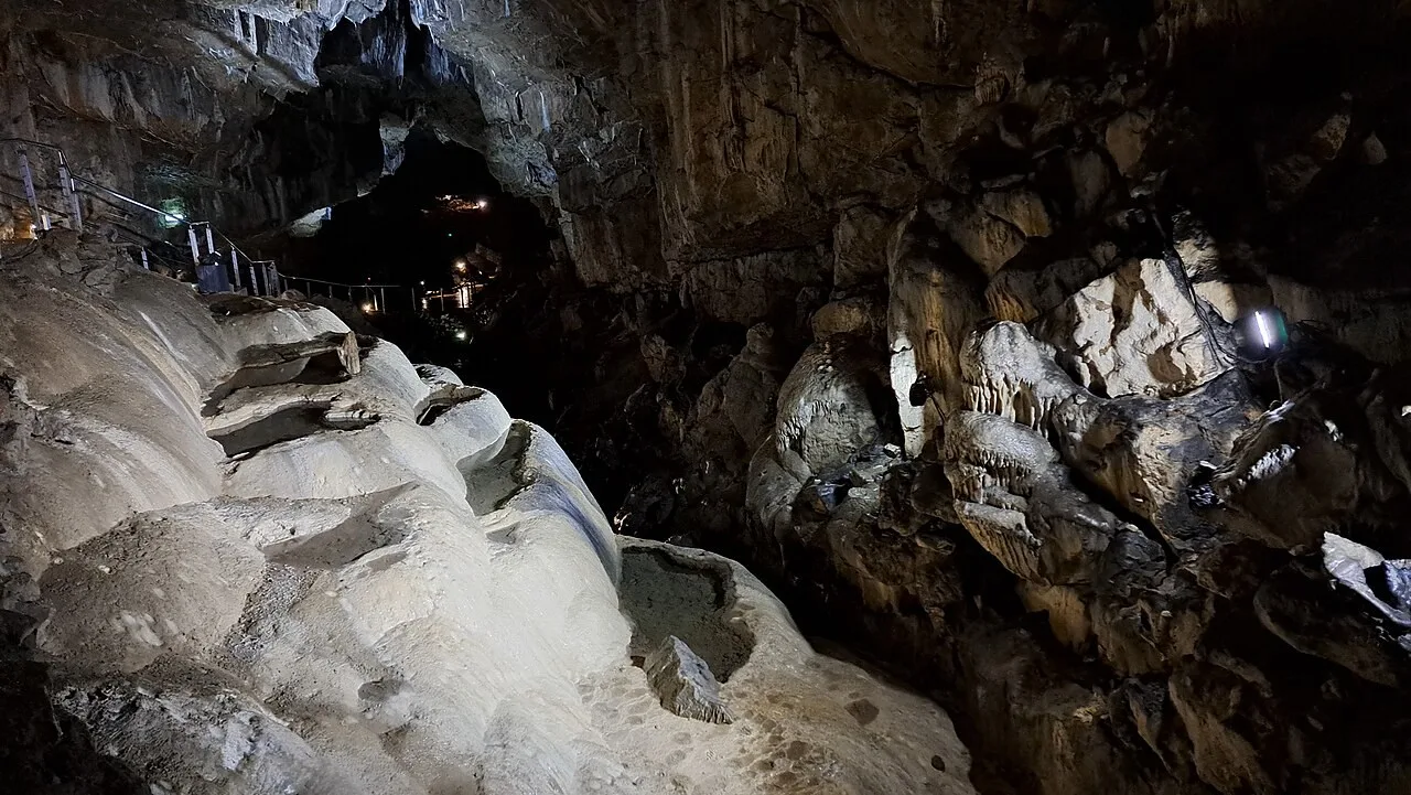 Illuminated limestone formations and visitor walkway inside Poole’s Cavern