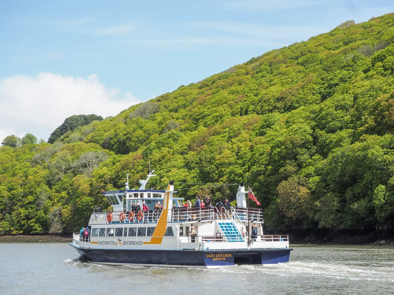 Dart Explorer cruising on the River Dart beside wooded banks