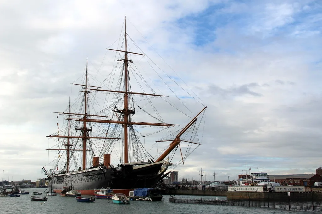 HMS Warrior’s black hull and masts beside the quay at Portsmouth Historic Dockyard