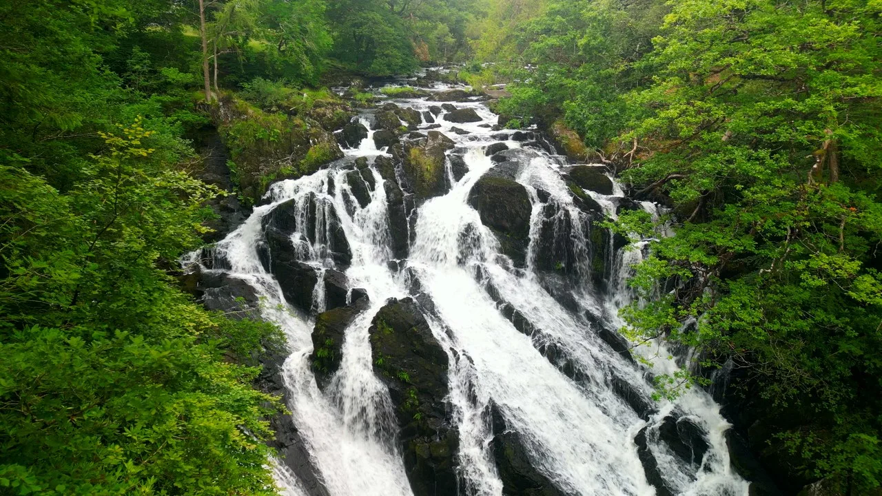 Aerial view of Swallow Falls cascading through green woodland