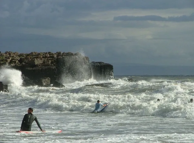 Surfers in the waves at Rest Bay, Porthcawl; contextual beach photograph
