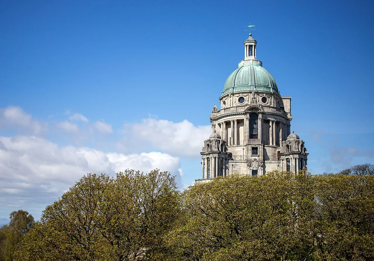 Copper dome and stone upper levels of Ashton Memorial above the trees in Williamson Park