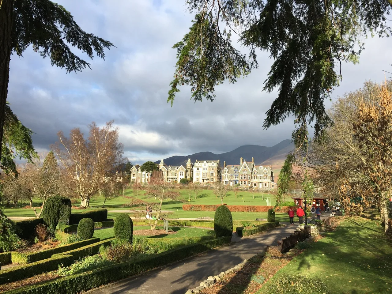 Paths, lawns and clipped shrubs in Hope Park with Keswick buildings beyond