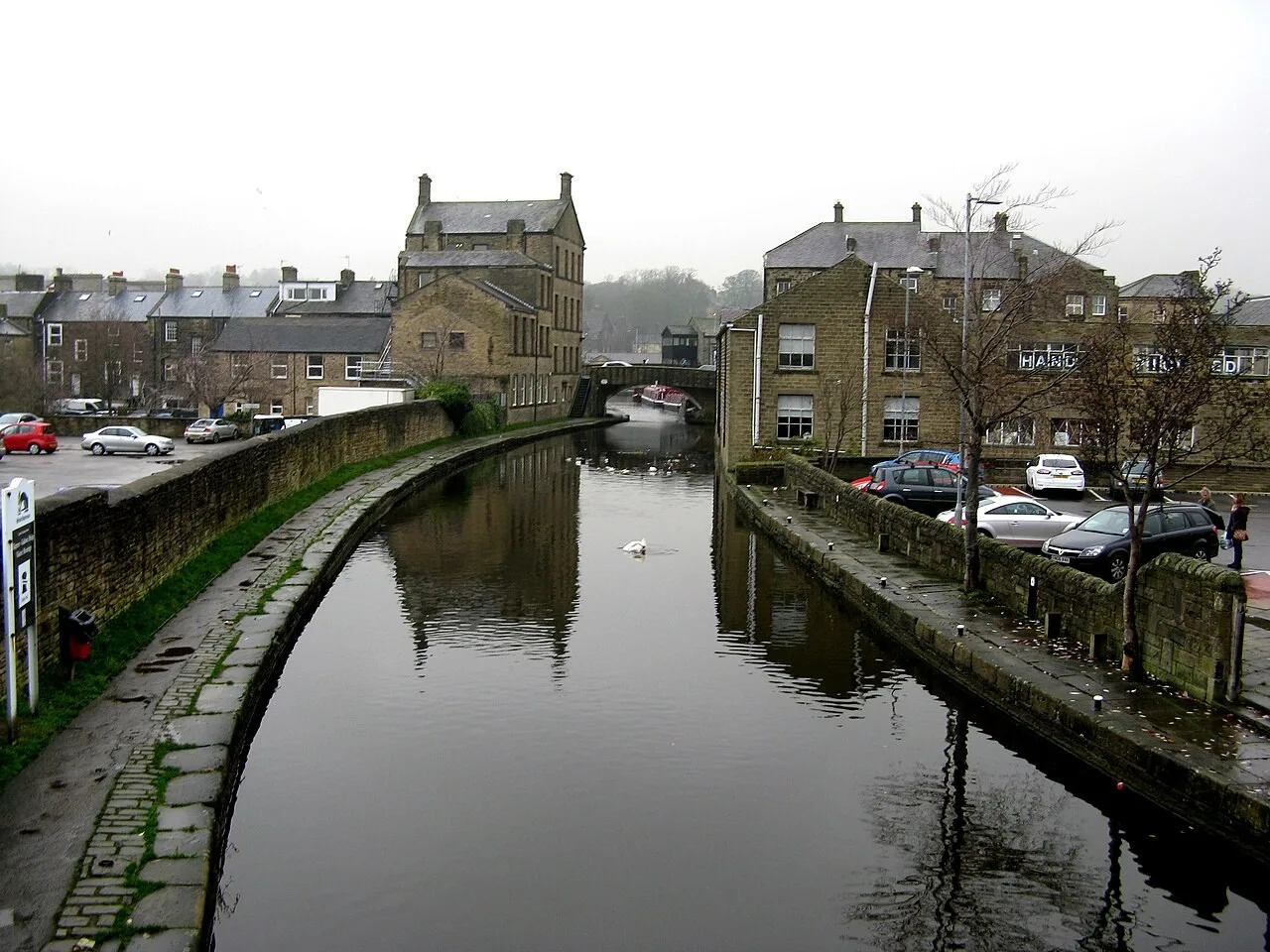 Canal and paved towpath between stone buildings in central Skipton