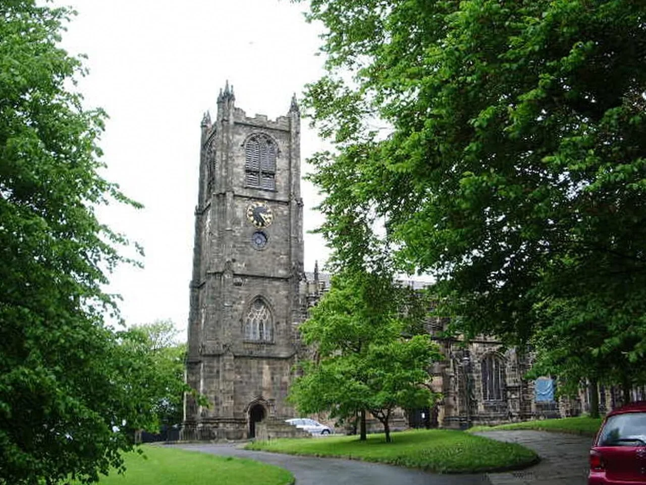 Lancaster Priory’s stone clock tower framed by leafy trees
