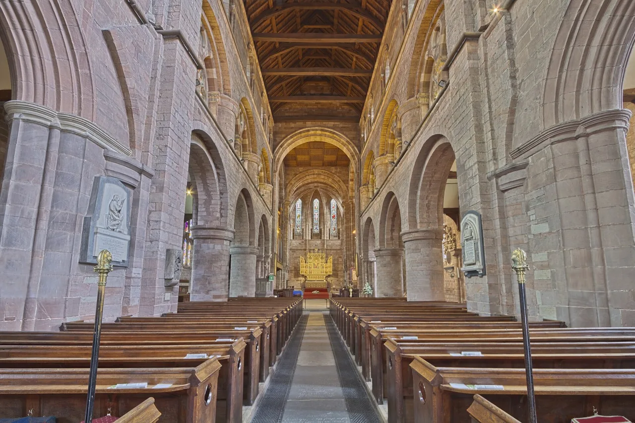 Norman arches and rows of pews inside Shrewsbury Abbey