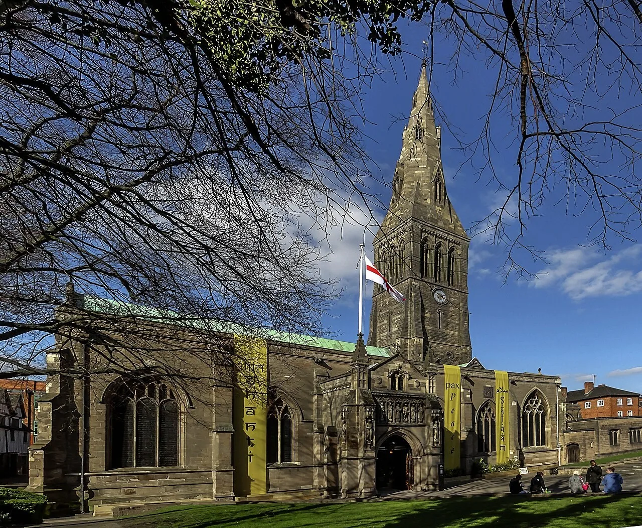 Stone tower and south side of Leicester Cathedral beneath a blue sky