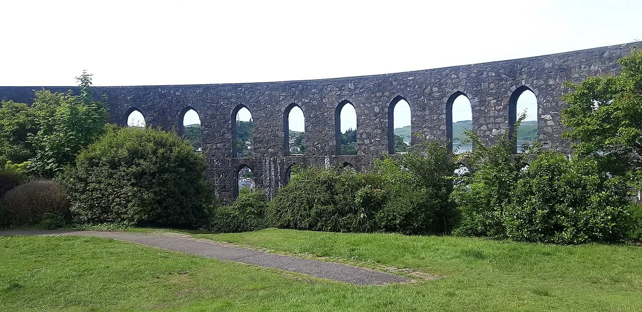 Stone arches of McCaig’s Tower behind the grass and paths of its open-air garden
