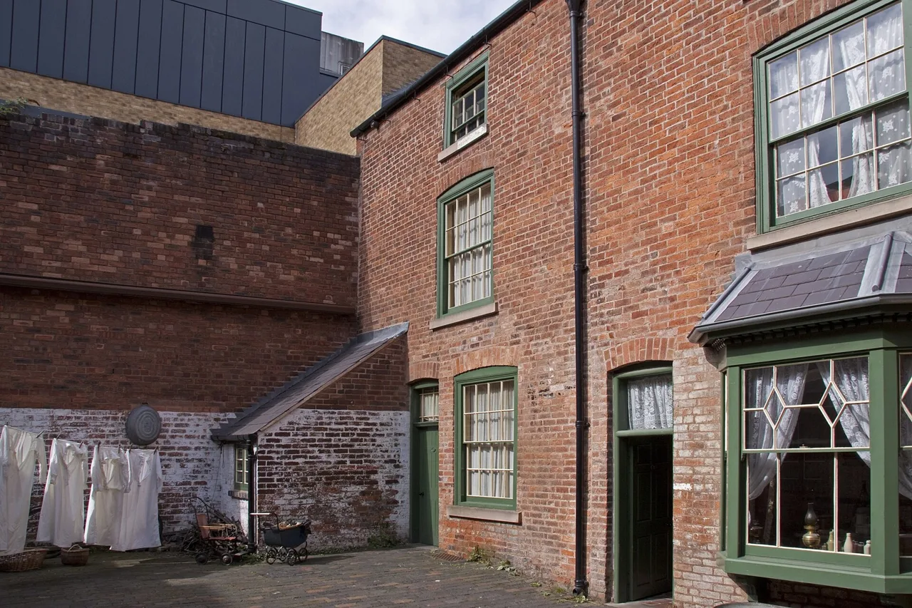 Brick houses, green window frames and washing in the Birmingham Back to Backs courtyard