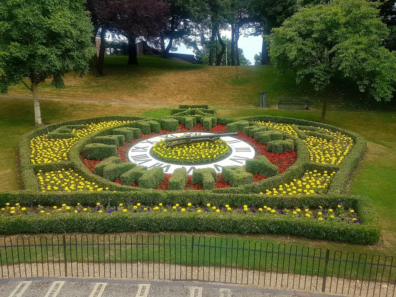 The planted floral clock surrounded by trees and lawn in Pannett Park
