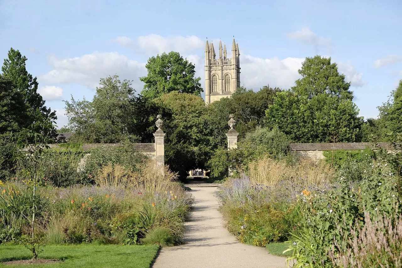 Planting and a central path in Oxford Botanic Garden with Magdalen Tower beyond