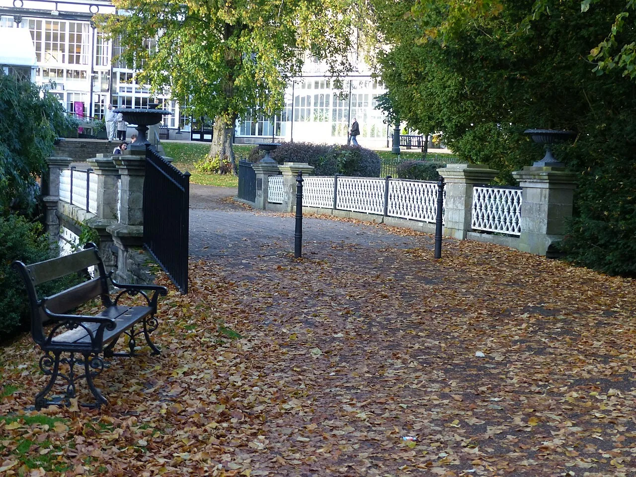 Leaf-covered path and white-railed bridge beside Buxton’s Pavilion Gardens