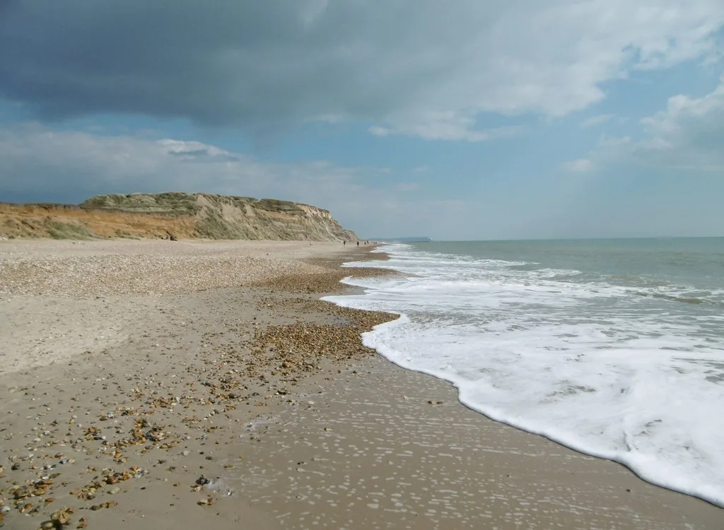 Waves meeting a sandy and shingle beach below Hengistbury Head